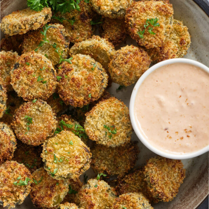 Air fried pickles on a platter with dipping sauce.