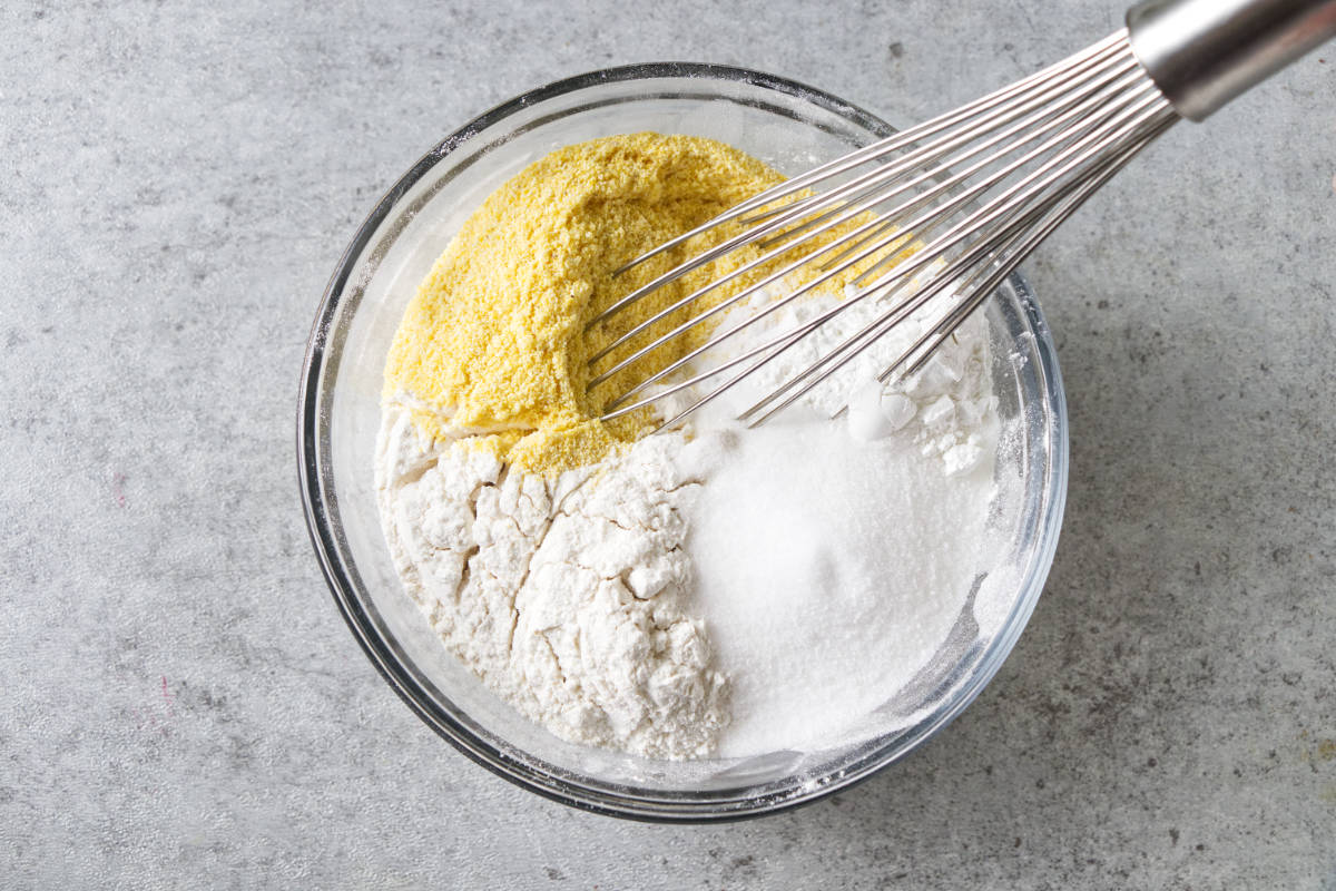 Combining flour, cornmeal, and leavening.