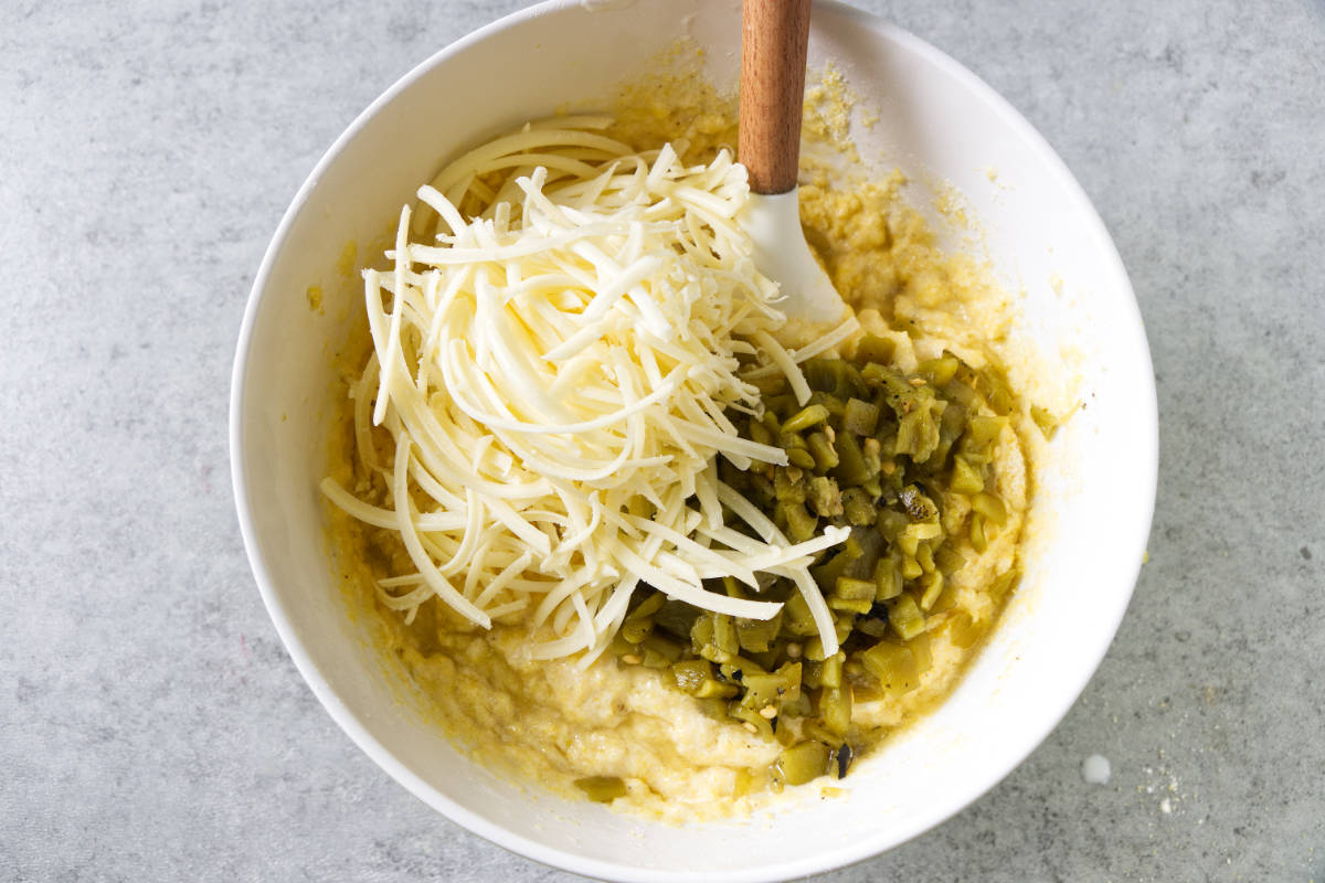 Adding cheese and green chiles to cornbread batter.