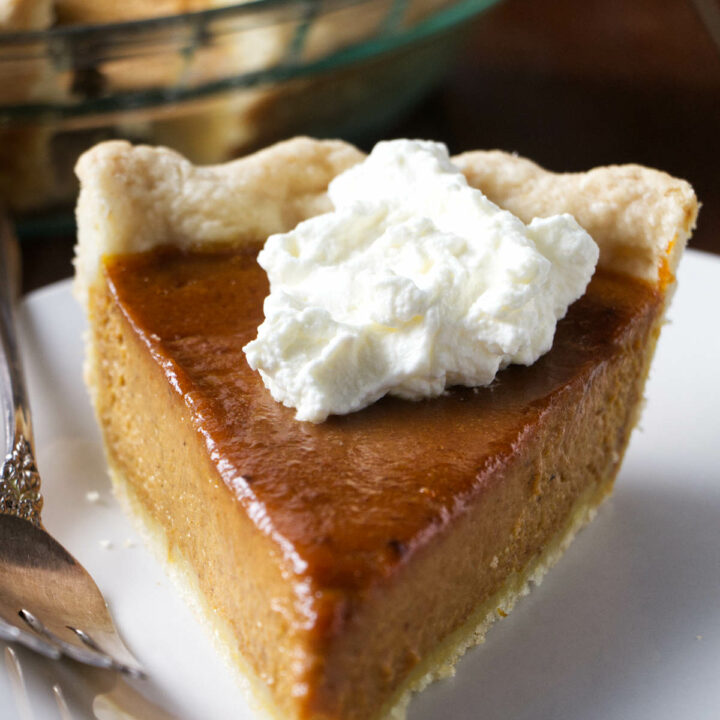 A slice of smoked pumpkin pie topped with bourbon whipped cream.