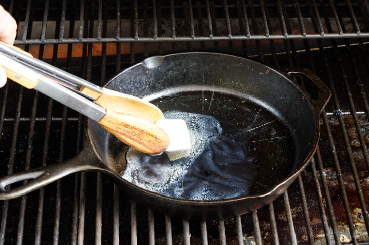Melting butter in a skillet on the grill.