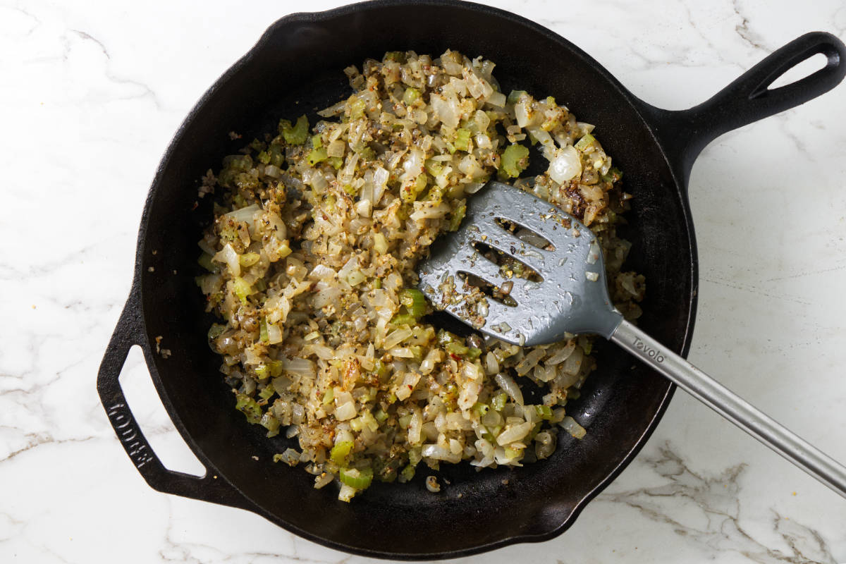 Cooking onions, celery and herbs in a skillet.