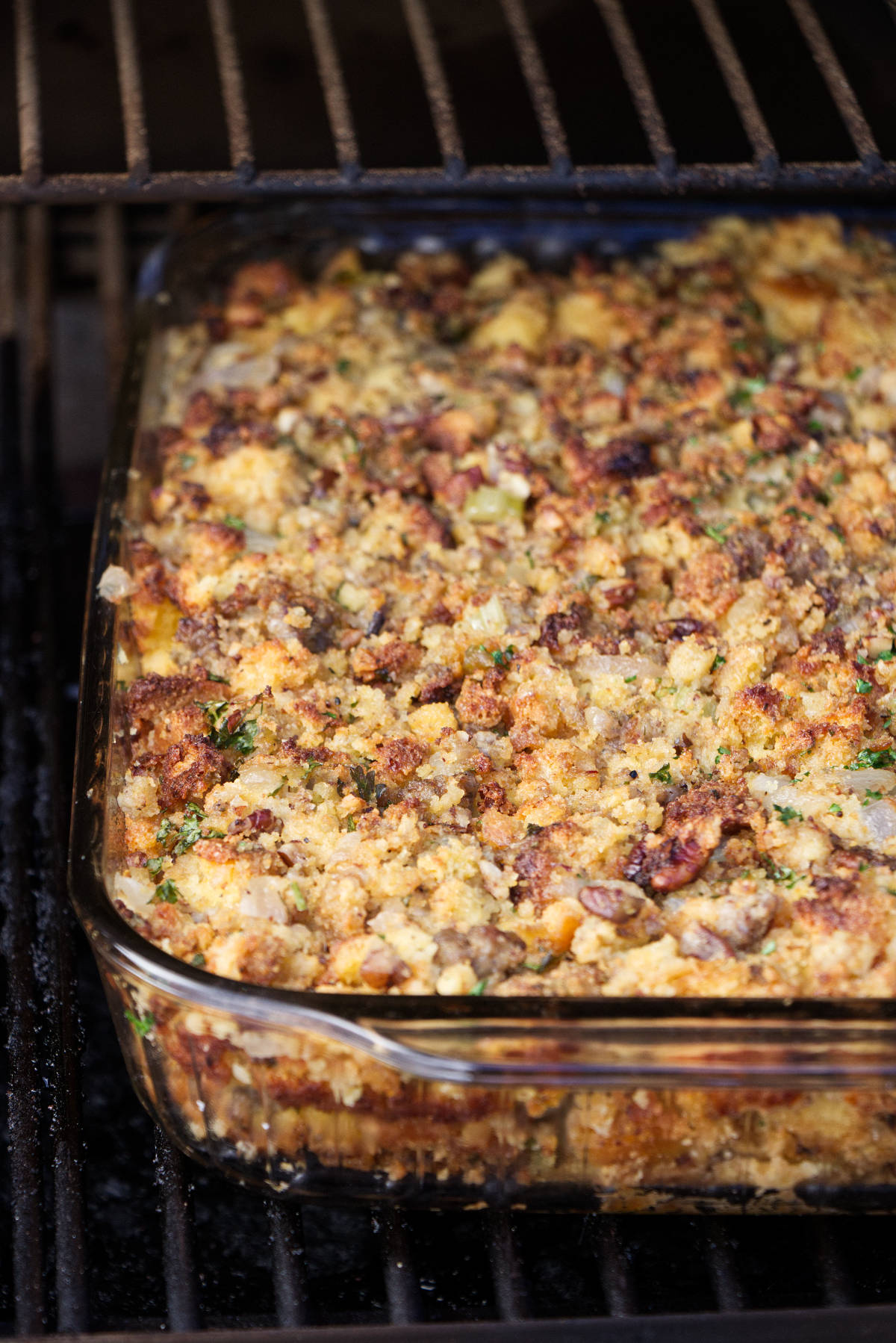 A casserole dish with stuffing in a Traeger grill.