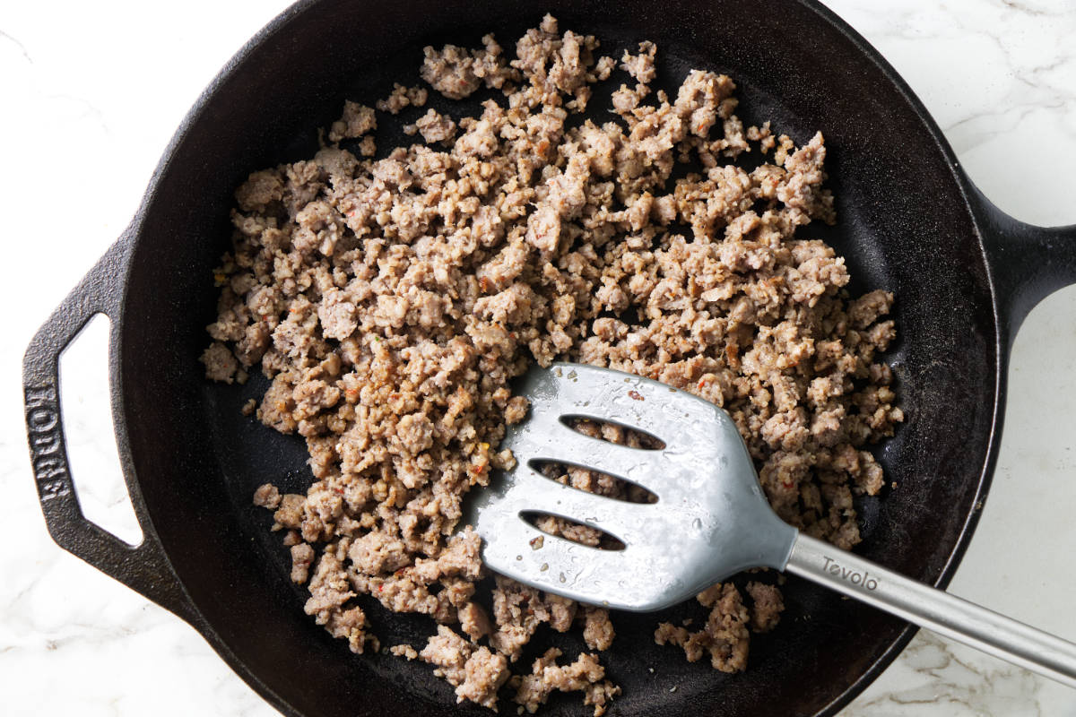 Cooking ground sausage in a cast iron pan.