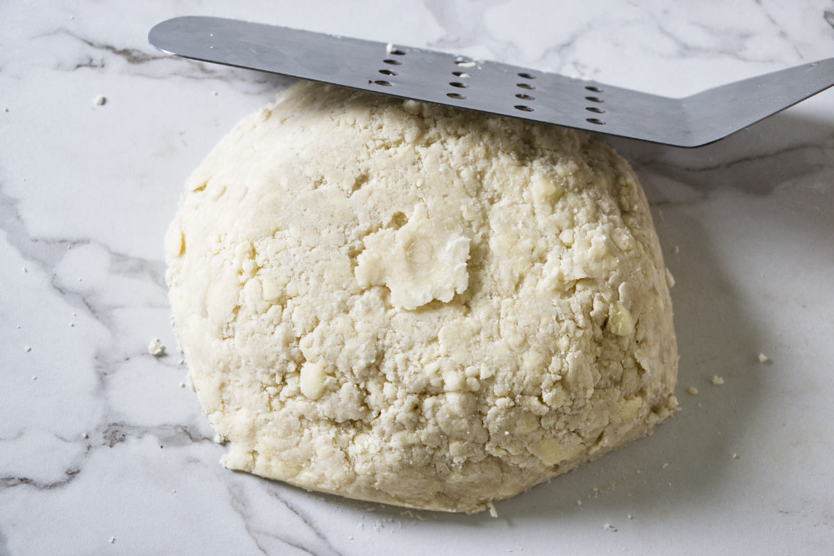 Pressing pie dough together on the counter.