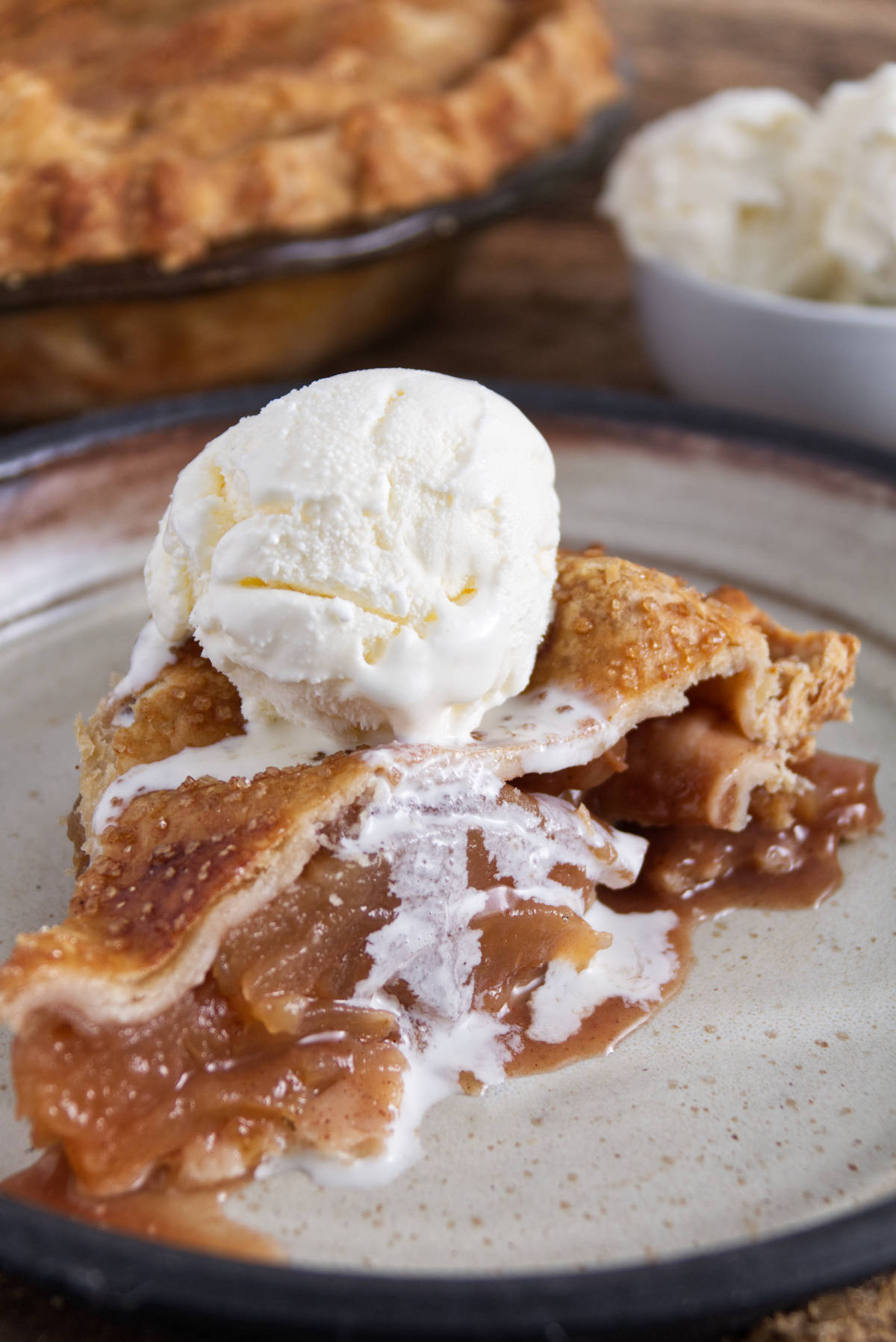 slice of apple pie on a white plate with a scoop of ice cream on top