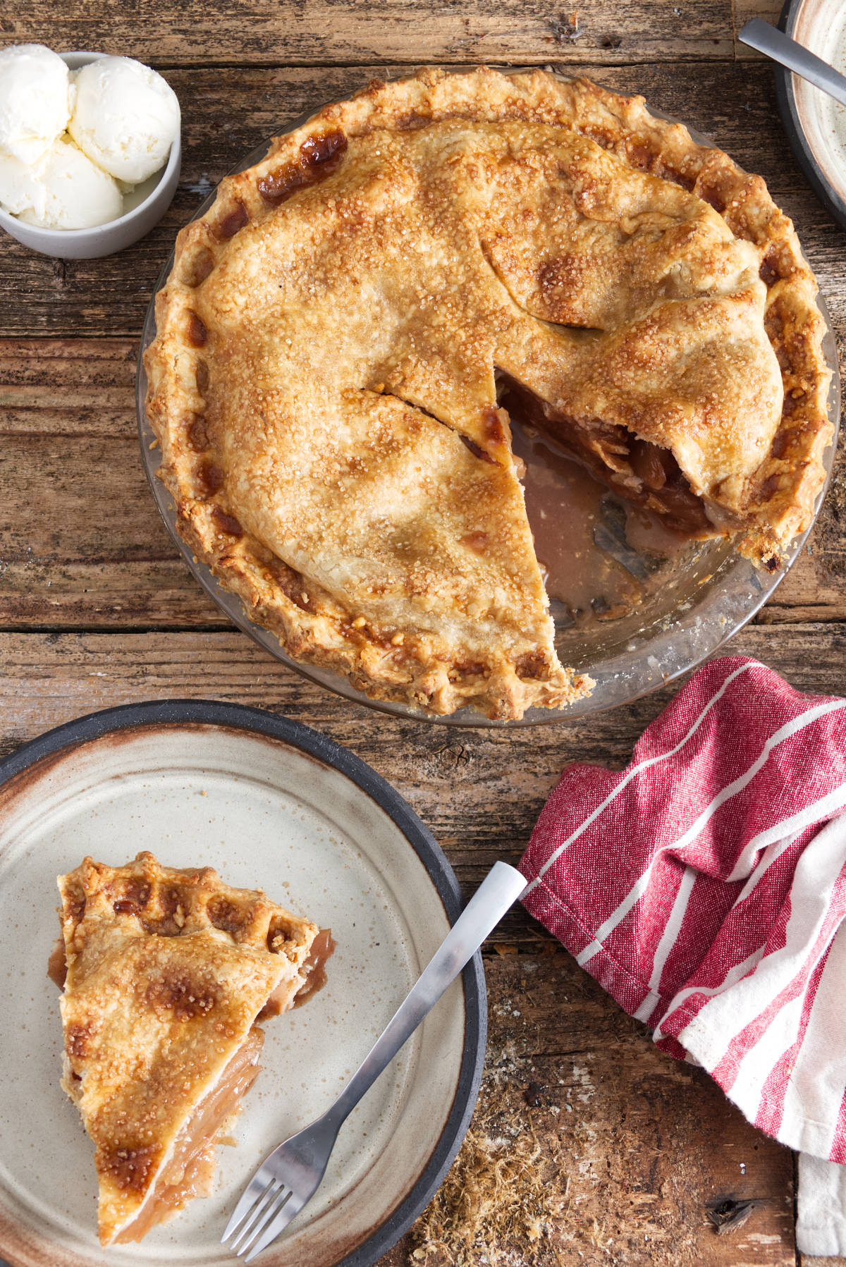 apple pie with slice out of it, slice of apple pie on plate, bowl with three scoops of vanilla ice cream