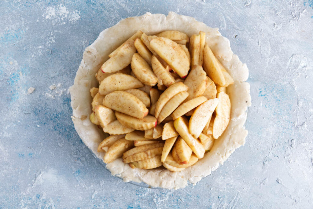 apple pie filling in pie crust ready to be topped with more pie crust