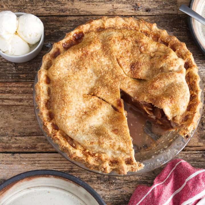 apple pie with slice out of it, slice of apple pie on plate, bowl with three scoops of vanilla ice cream