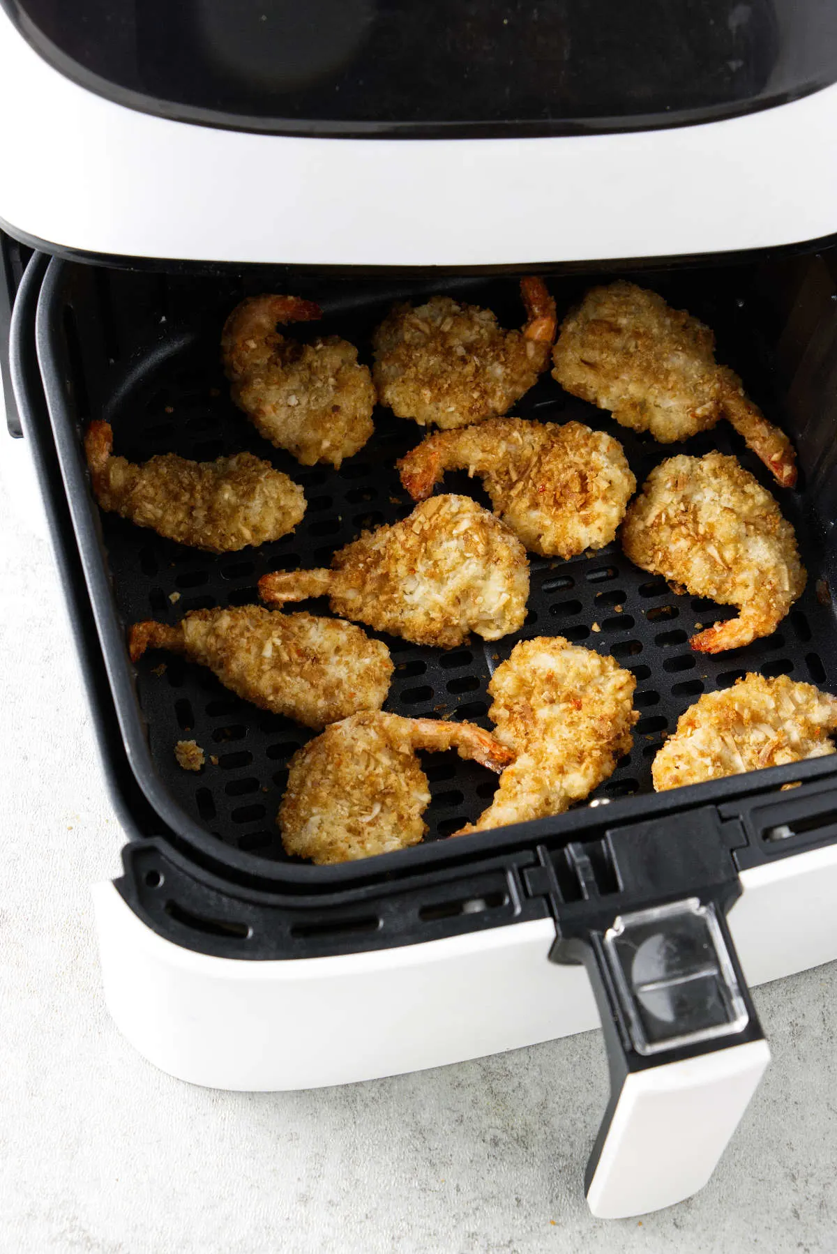 Breaded shrimp cooking in an air fryer.