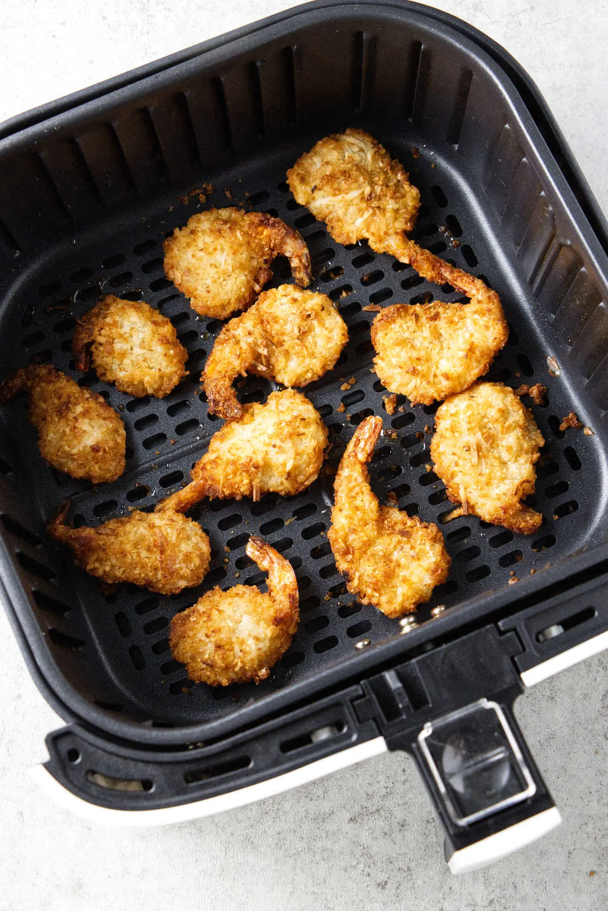 Coconut shrimp in an air fryer basket.
