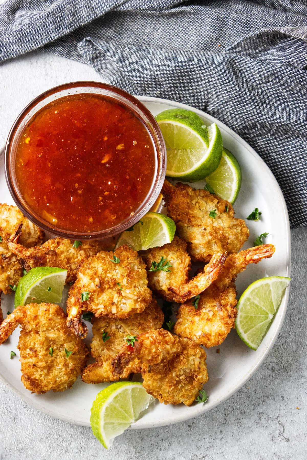 A plate of coconut shrimp and lime wedges next to a dish of dipping sauce.