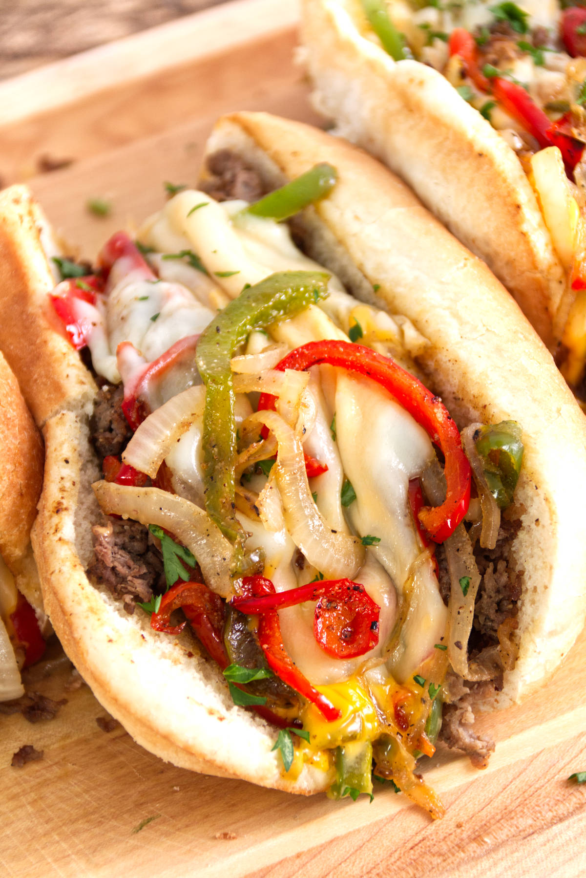 close up photo of philly cheesesteak loaded with steak, red and green peppers, gooey cheese whiz, and provolone