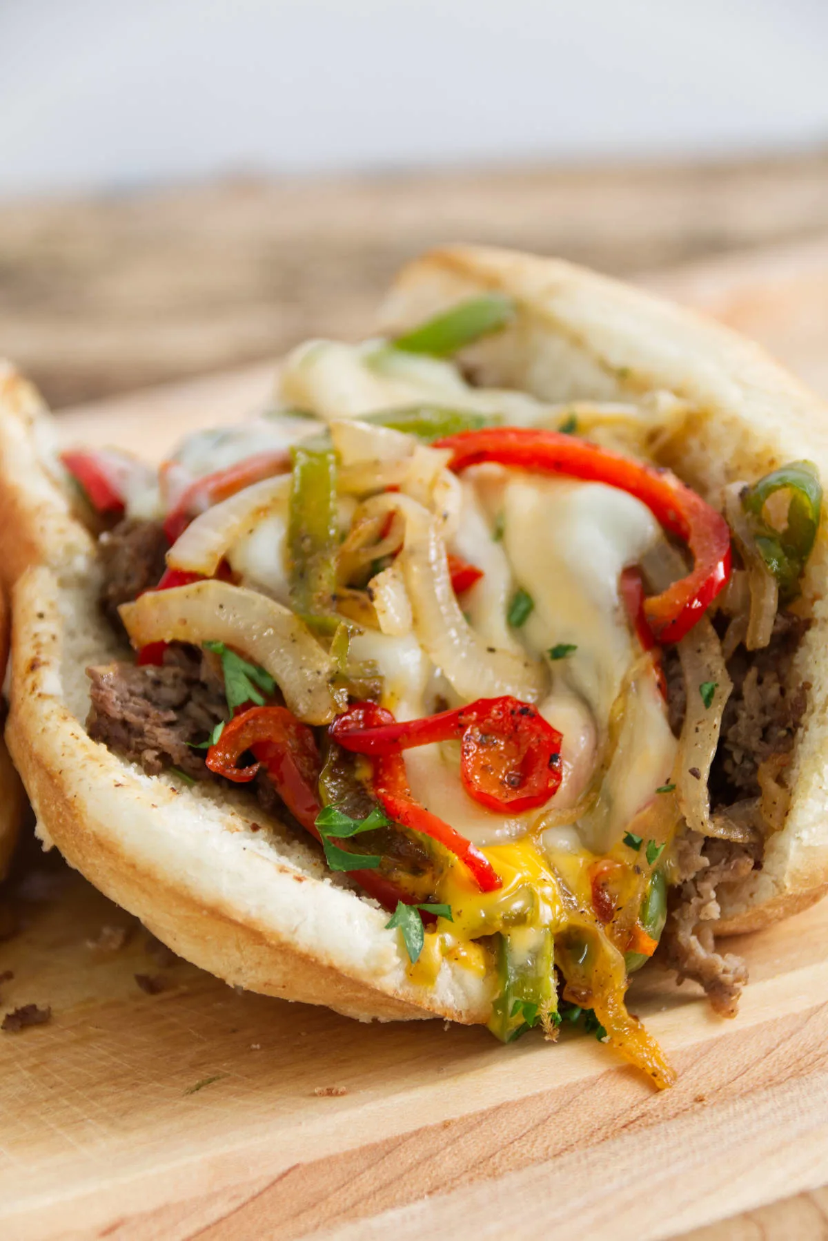close up of a blackstone philly cheese steak loaded with green and red peppers, melted provolone cheese, steak, and cheese whiz on a hoagie roll