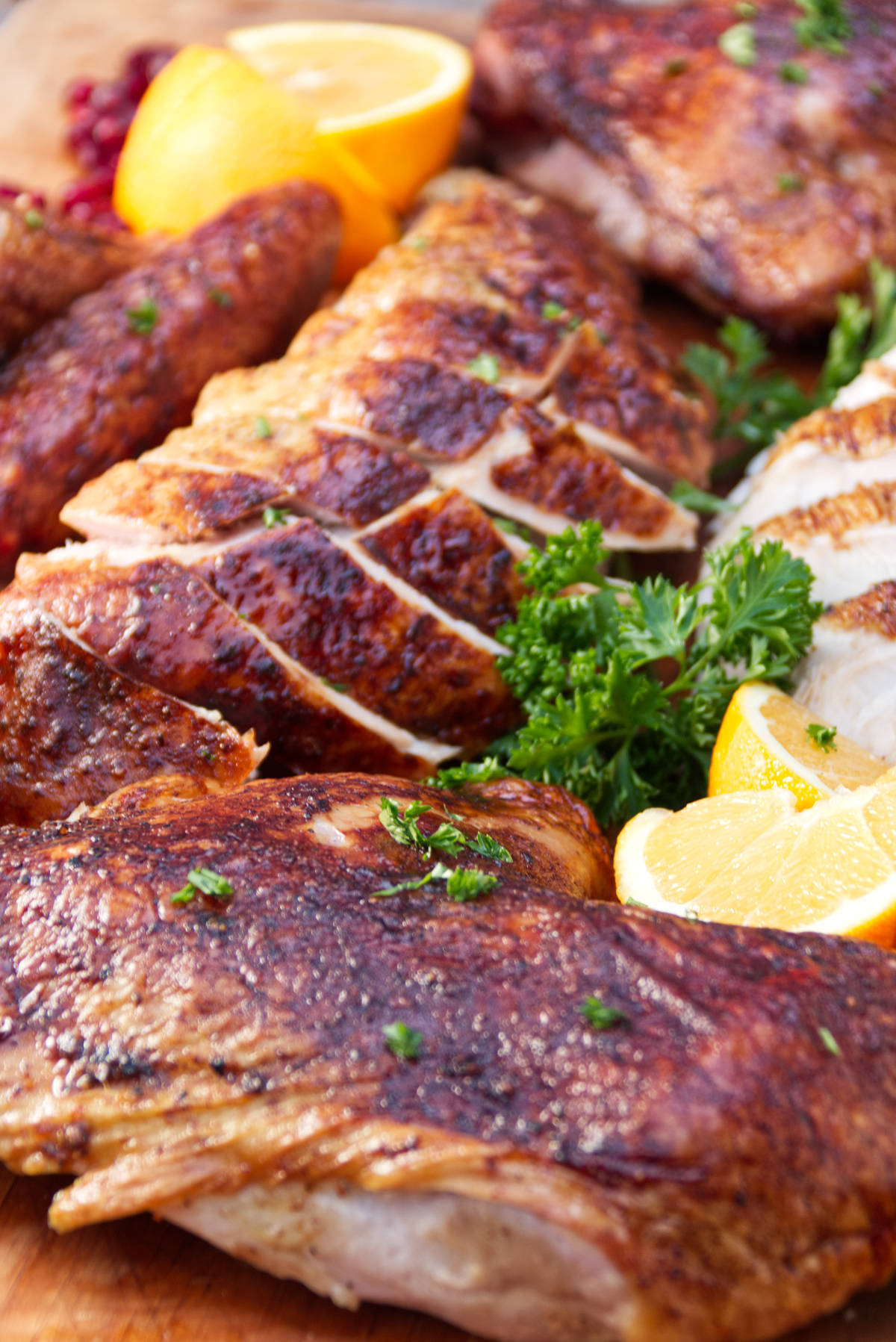 Traeger smoked spatchcock turkey with perfectly browned skin carved on a cutting board with parsley and orange slices as garnish