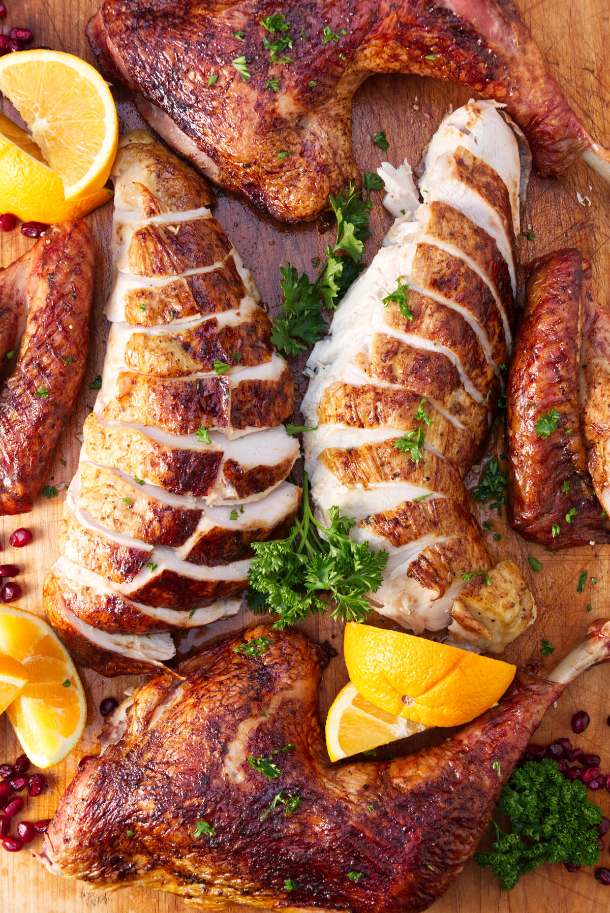 Traeger smoked spatchcock turkey carved on a cutting board with parsley and orange slices as garnish