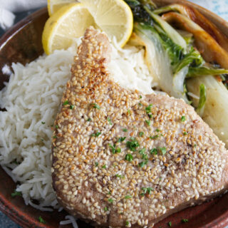sesame crusted whole ahi tuna steaks plated on a bed of rice