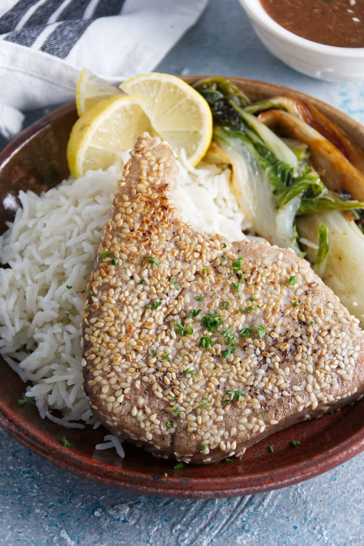 sesame crusted whole ahi tuna steaks plated on a bed of rice