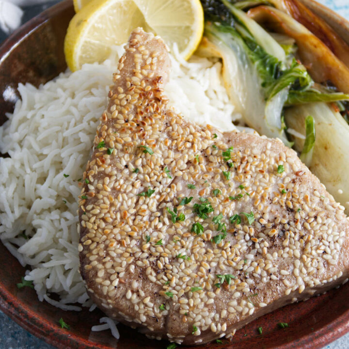 sesame crusted whole ahi tuna steaks plated on a bed of rice