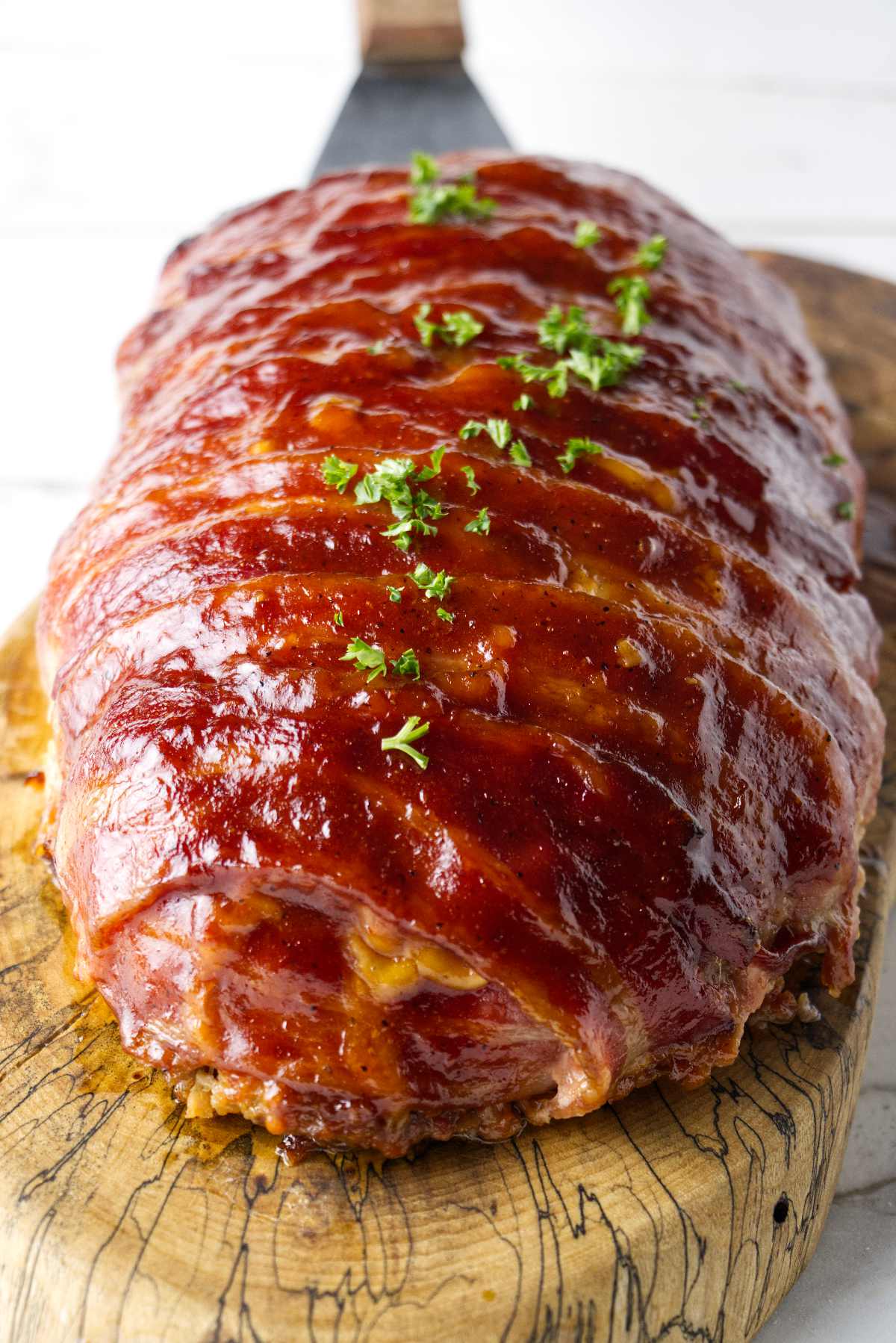 Bacon wrapped smoked meatloaf on a wood cutting board