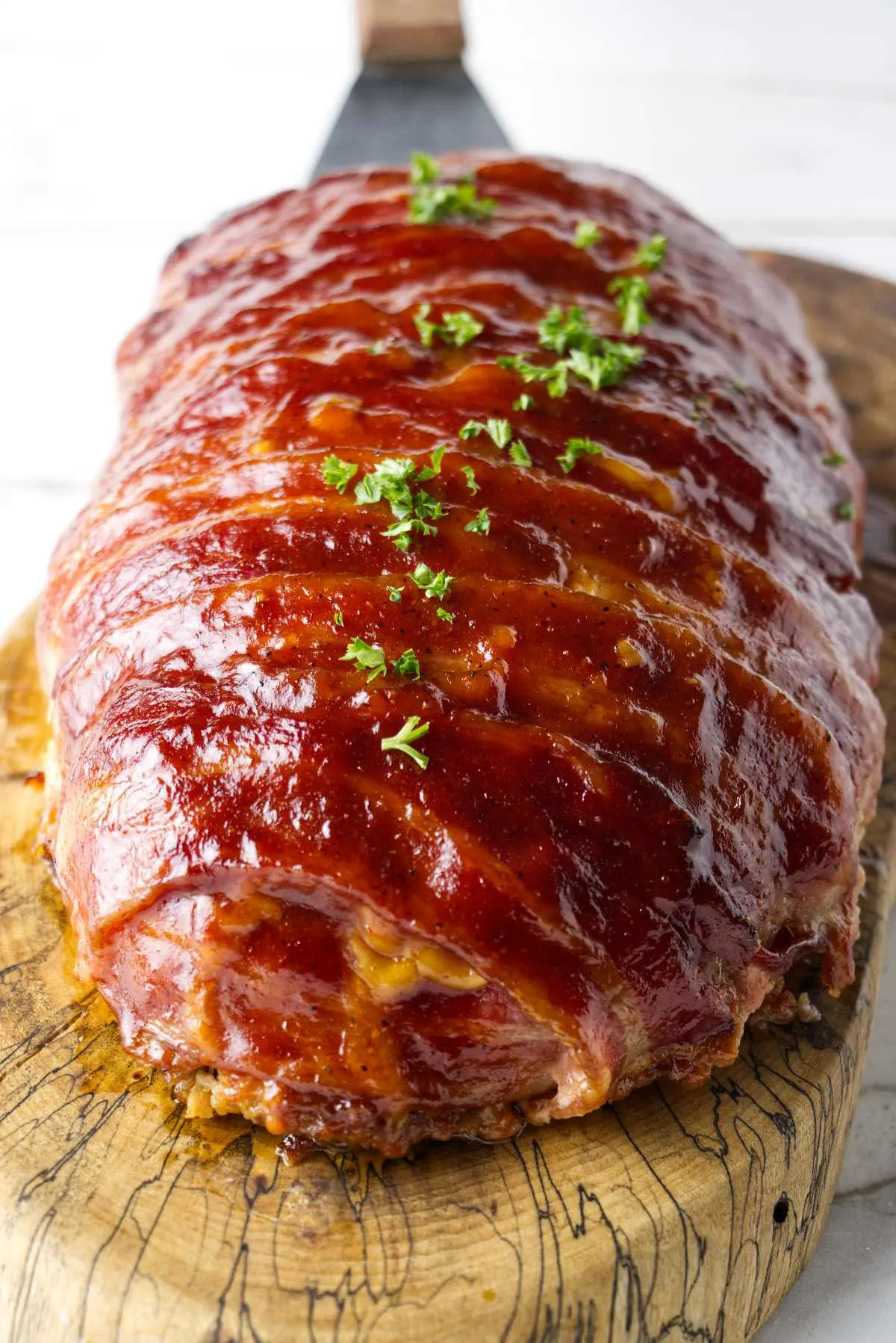Bacon wrapped smoked meatloaf on a wood cutting board