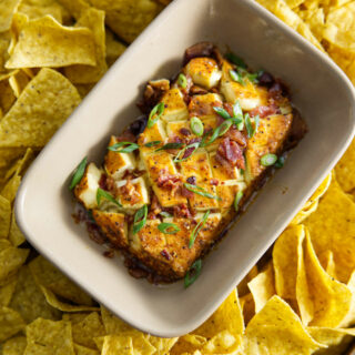 smoked cream cheese in dish surrounded by chips and topped with bacon and scallions