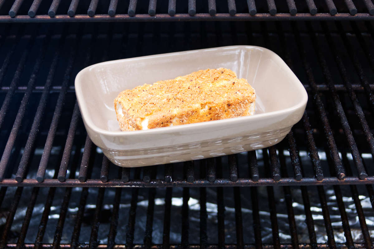 block of cream cheese in baking dish sitting on Traeger grates