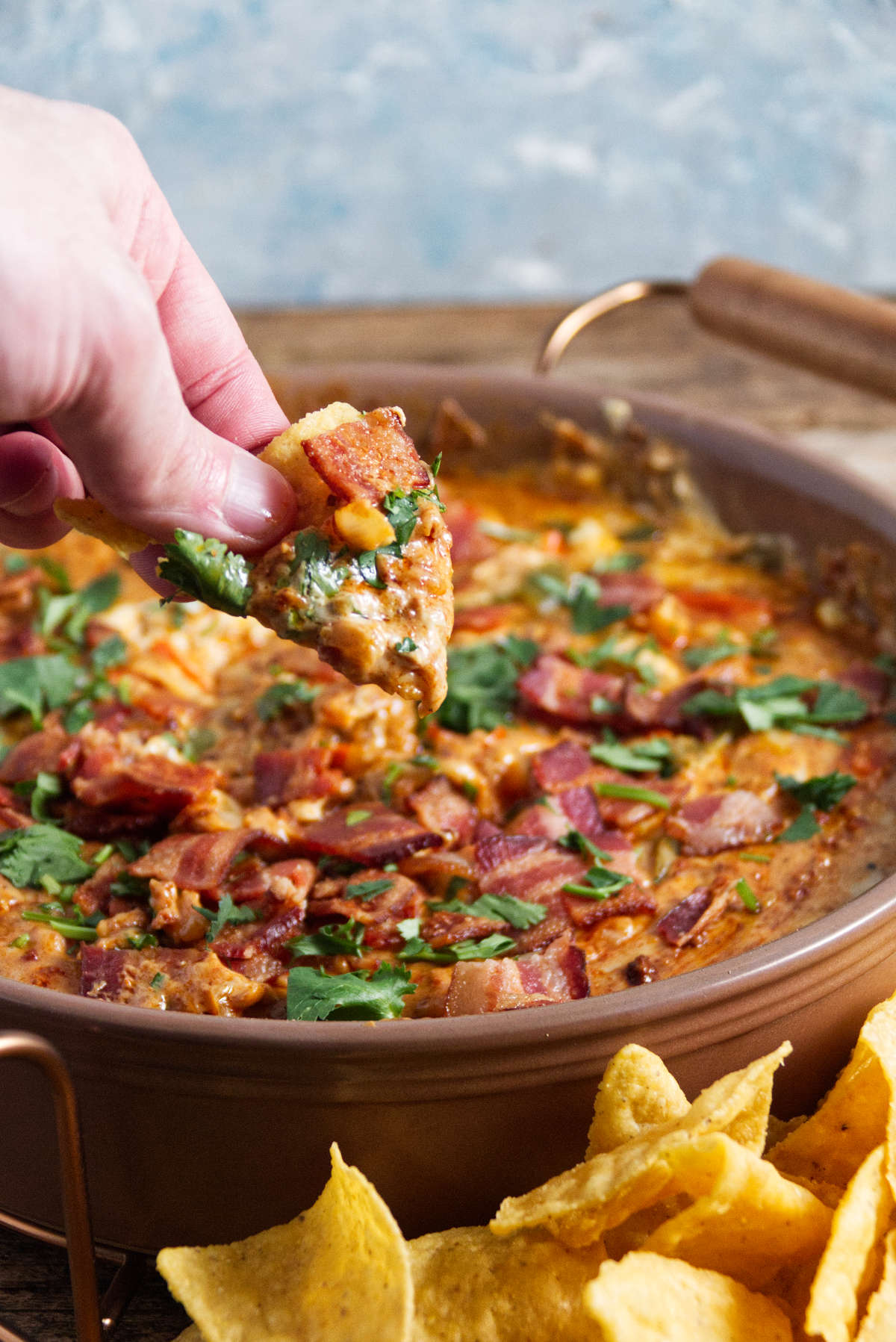 chip being dipped into large bowl of smoked queso dip