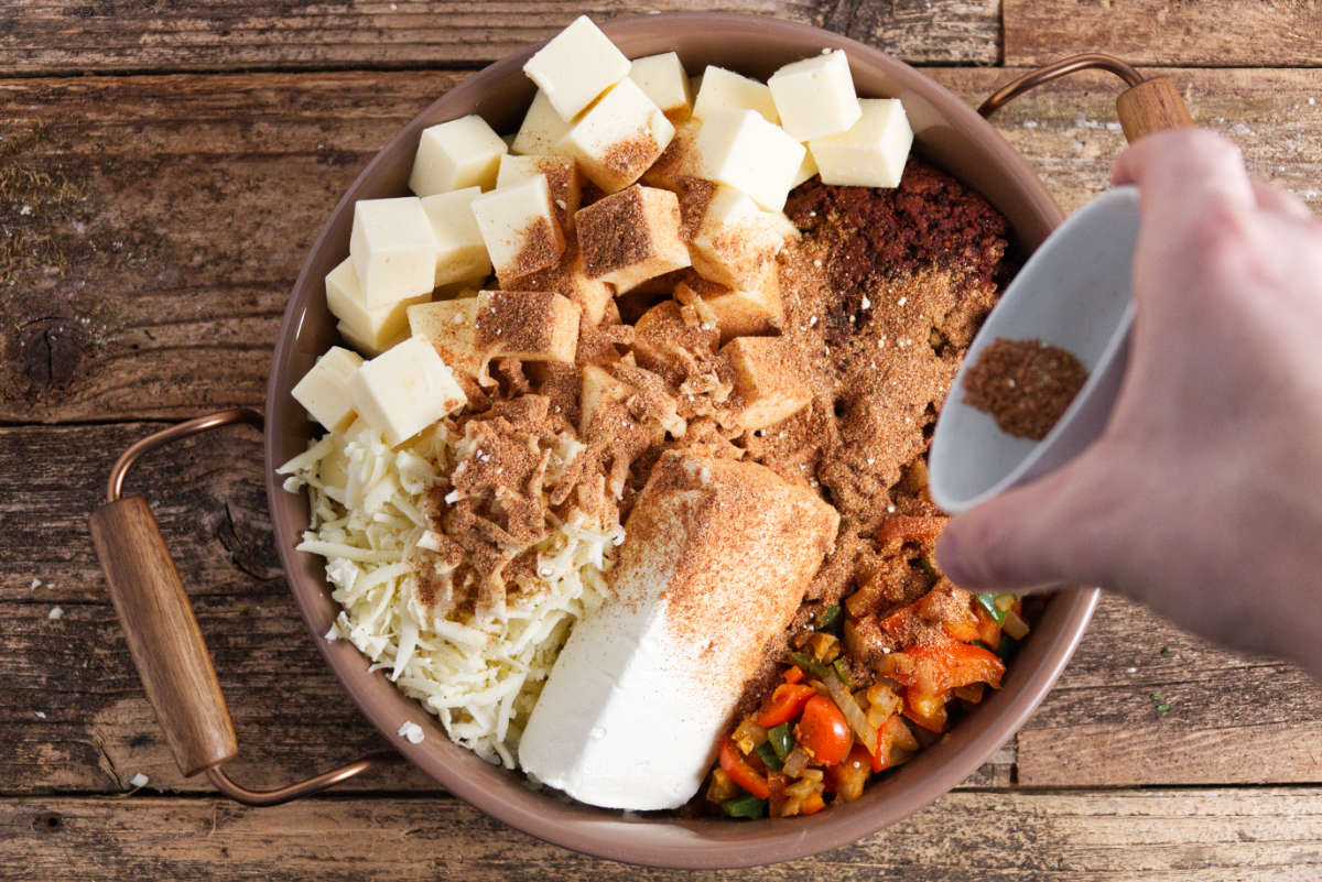 ingredients for smoked queso dip assembled in pan with seasoning