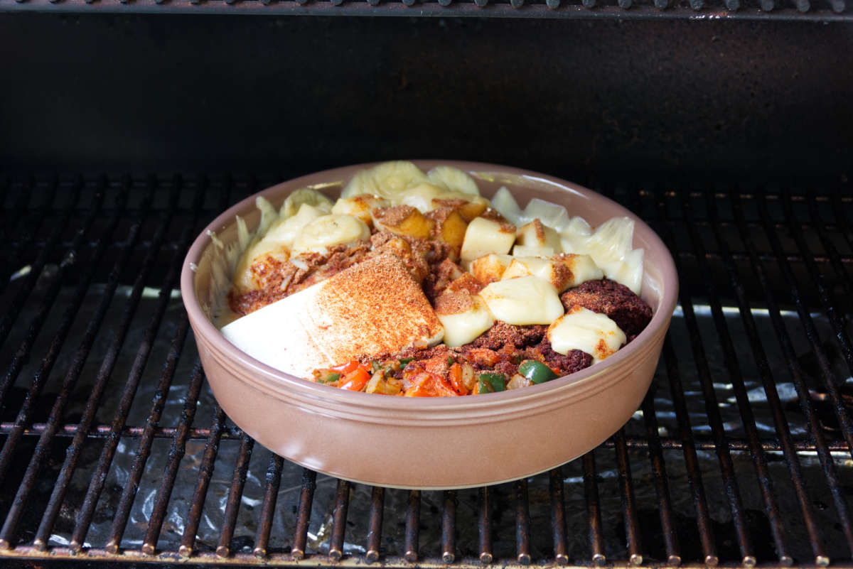 ingredients for queso dip assembled in baking pan on Traeger grates