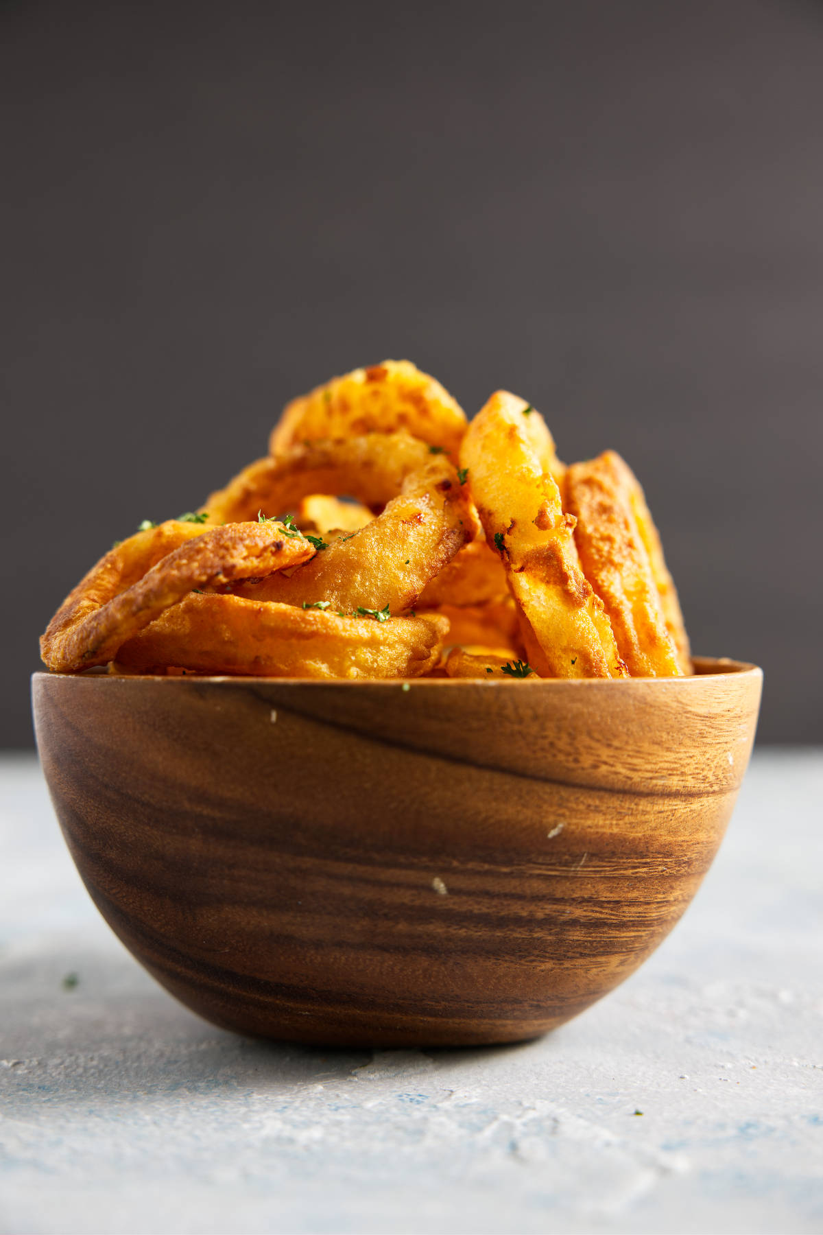 Crispy air fryer onion rings stacked in a wooden bowl