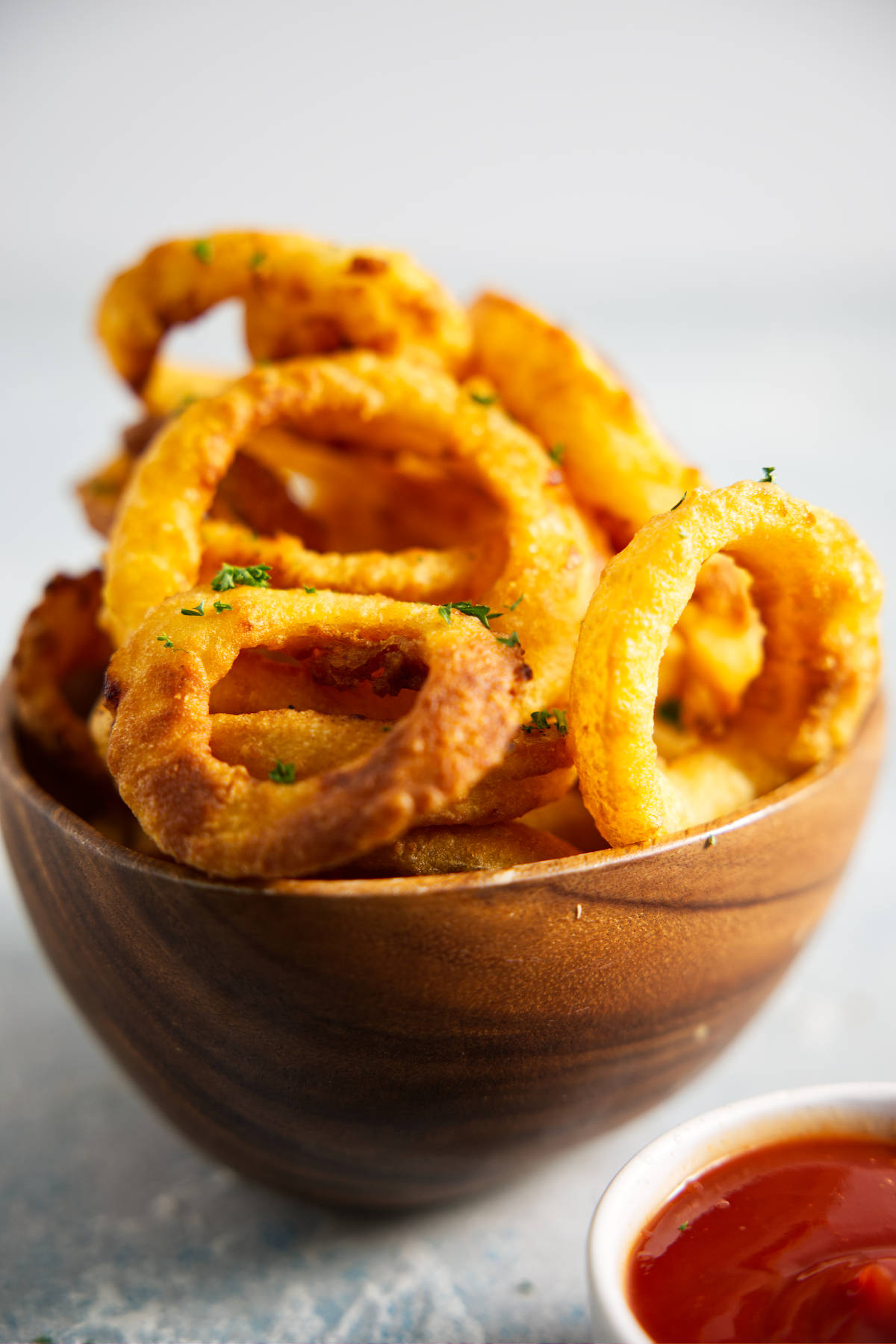 Wooden bowl filled with onion rings, bowl of ketchup