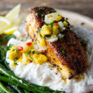 perfectly cooked halibut fillet with mango pineapple salsa on top