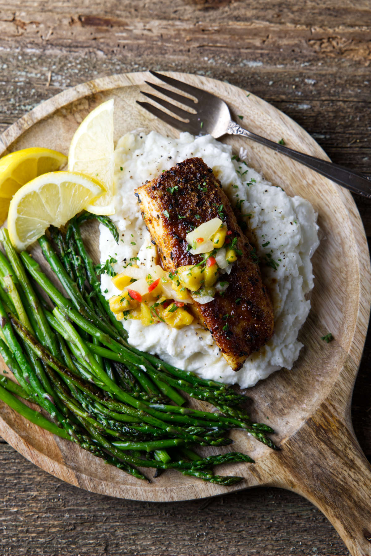 air fryer halibut plated on a bed of mashed potatoes and asparagus with mango salsa