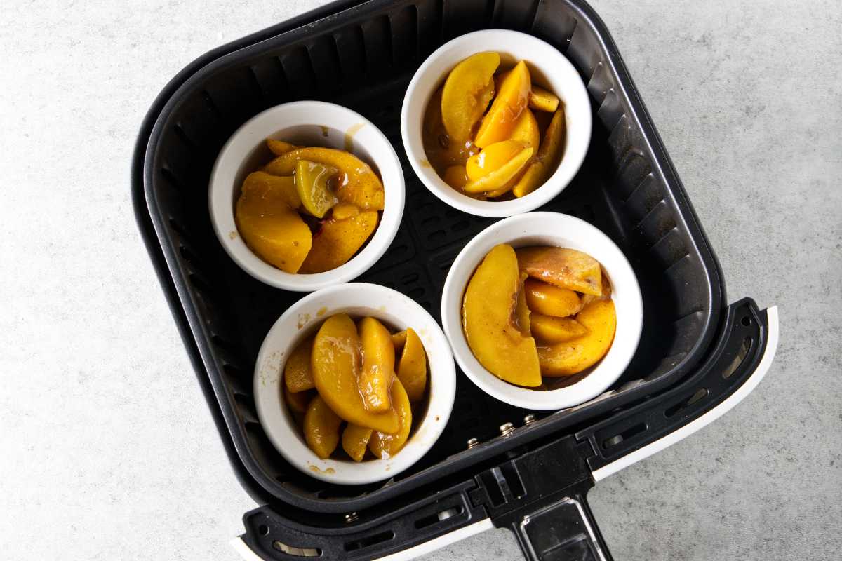 peach cobbler filling in ramekins in the air fryer basket