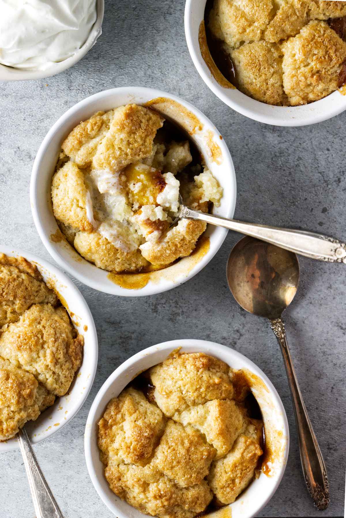 peach cobbler in ramekins with whipped cream on the side