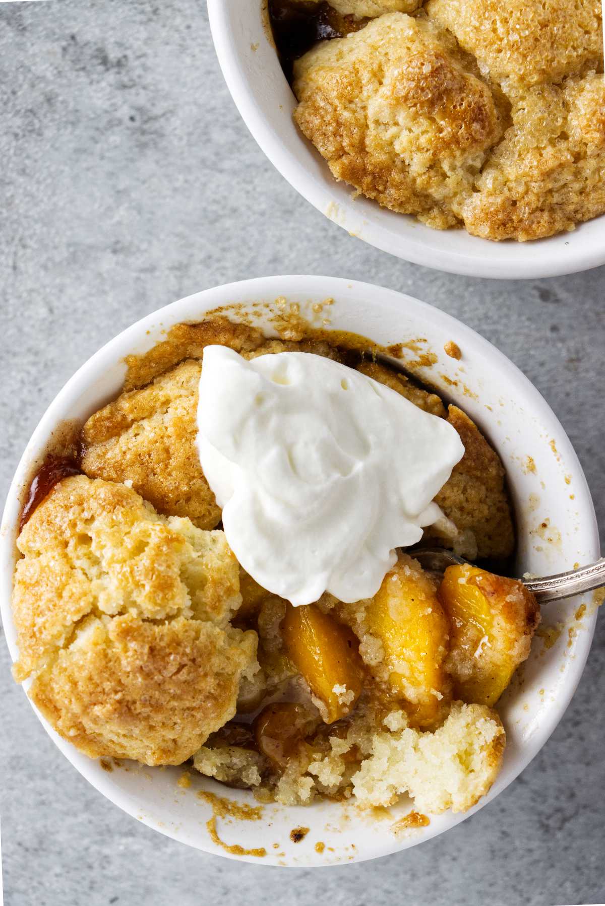 ramekin of air fryer peach cobbler with a dollop of whipped cream