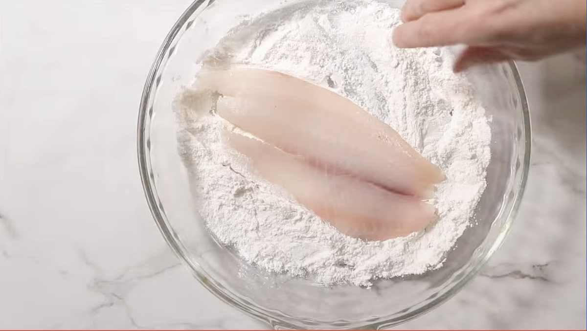 Dredging tilapia in flour.