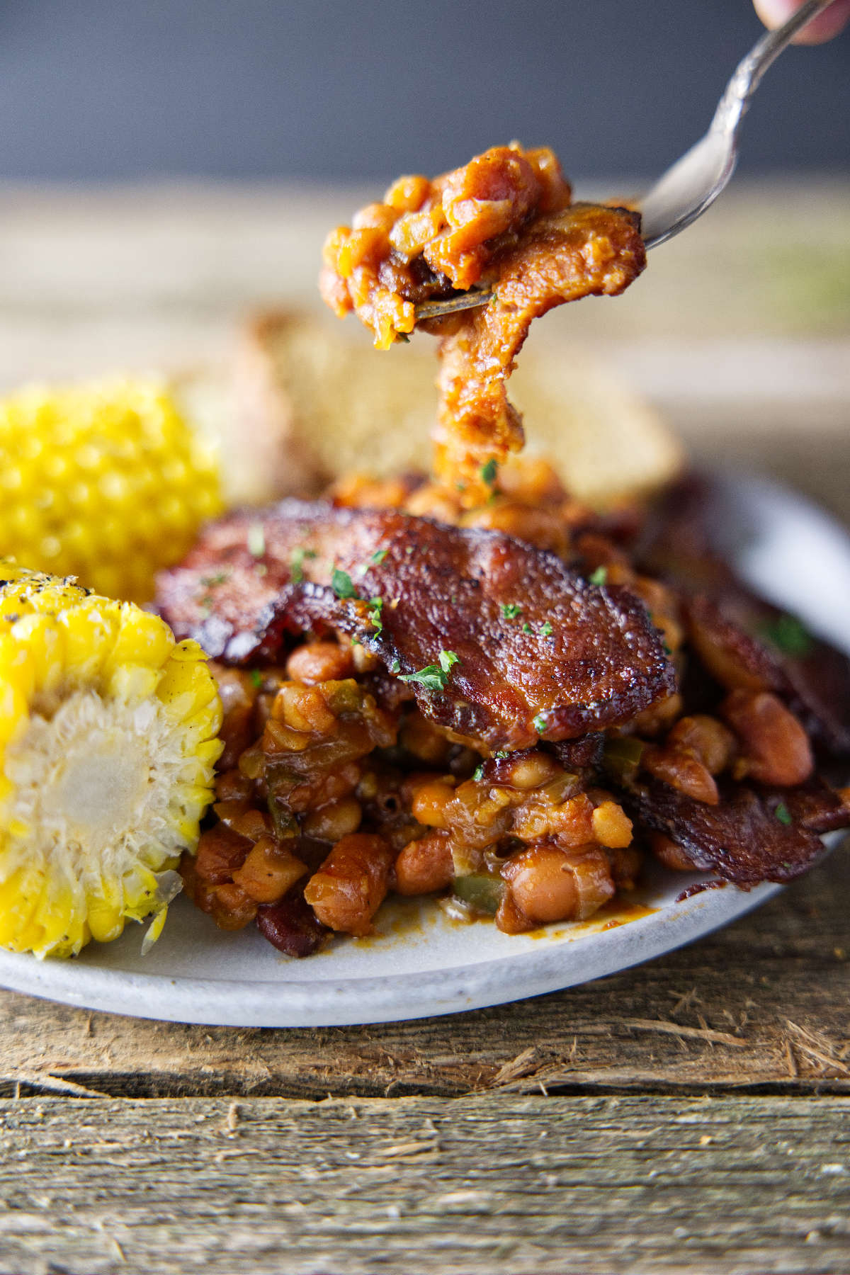 fork full of baked beans hovering over plate