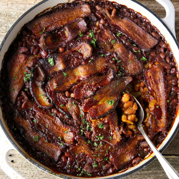 smoked baked beans in dutch oven with bacon laid on top