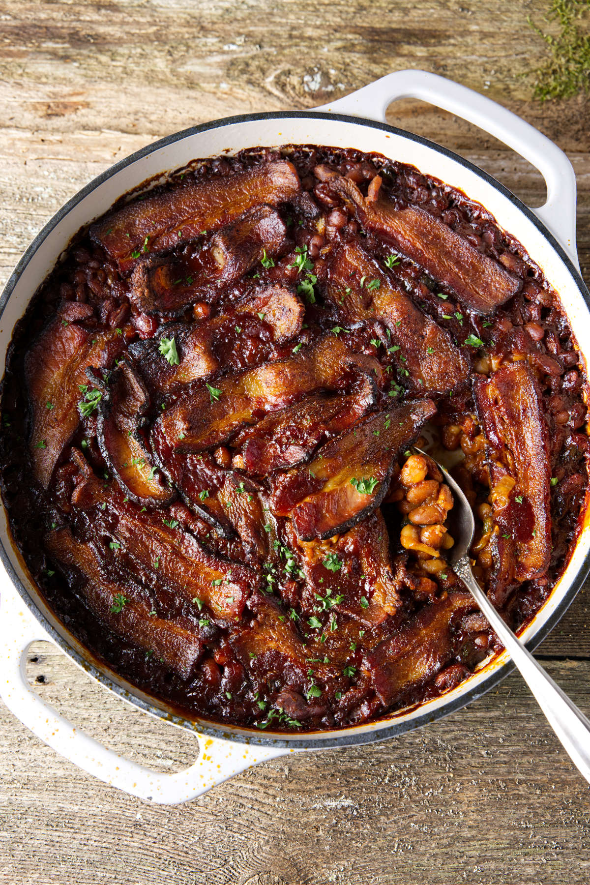 smoked baked beans in dutch oven with bacon laid on top