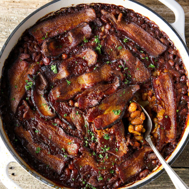 smoked baked beans in dutch oven with bacon laid on top