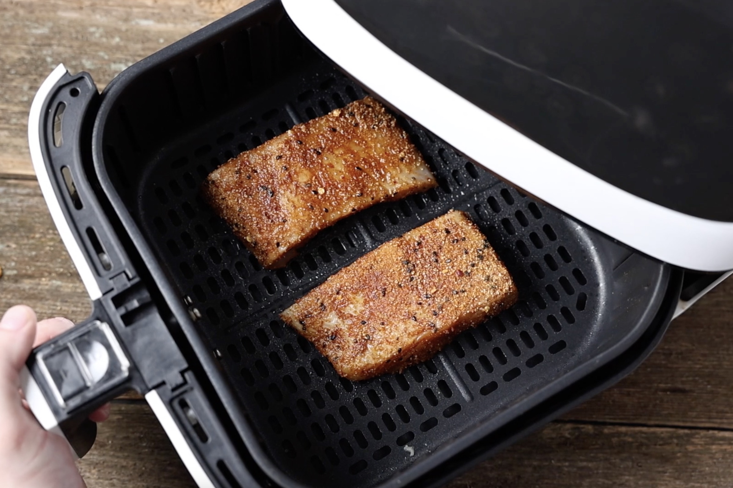 two seasoned halibut fillets in the air fryer basket