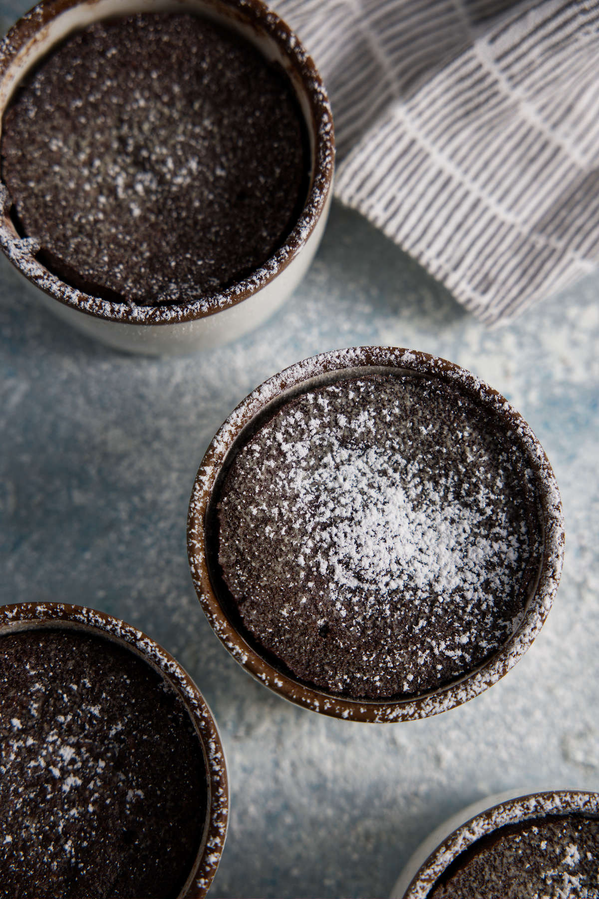 Air fryer mug cakes dusted with powdered sugar.