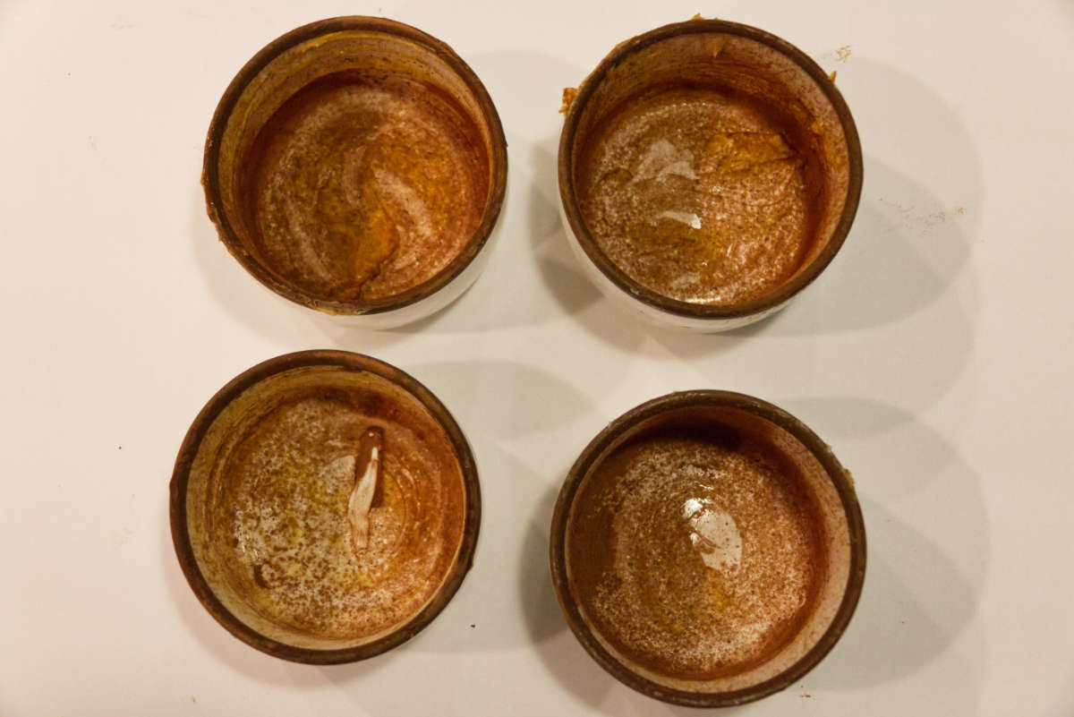 Preparing mugs with butter and cocoa powder.