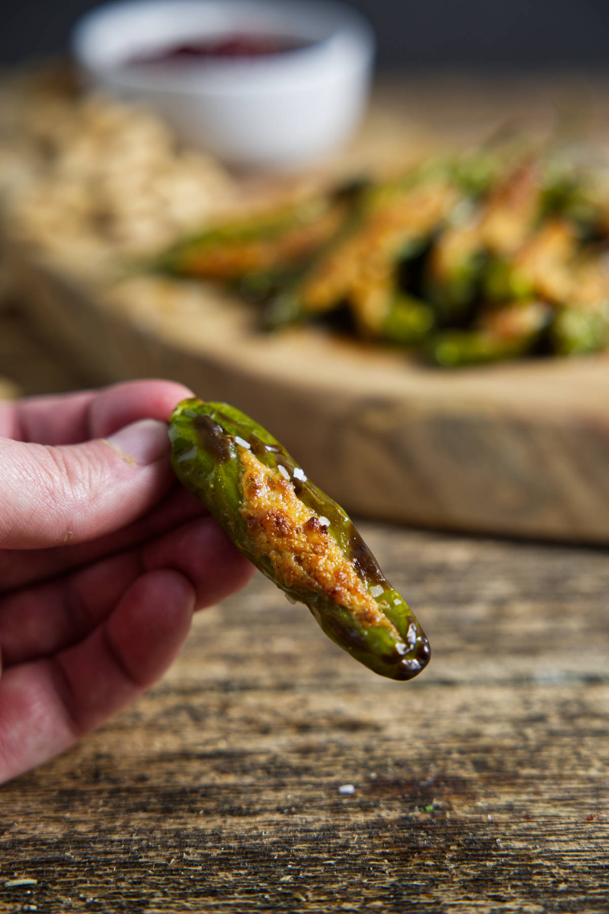 single stuffed shishito pepper with charred and blistered skin, stuffed with cheese