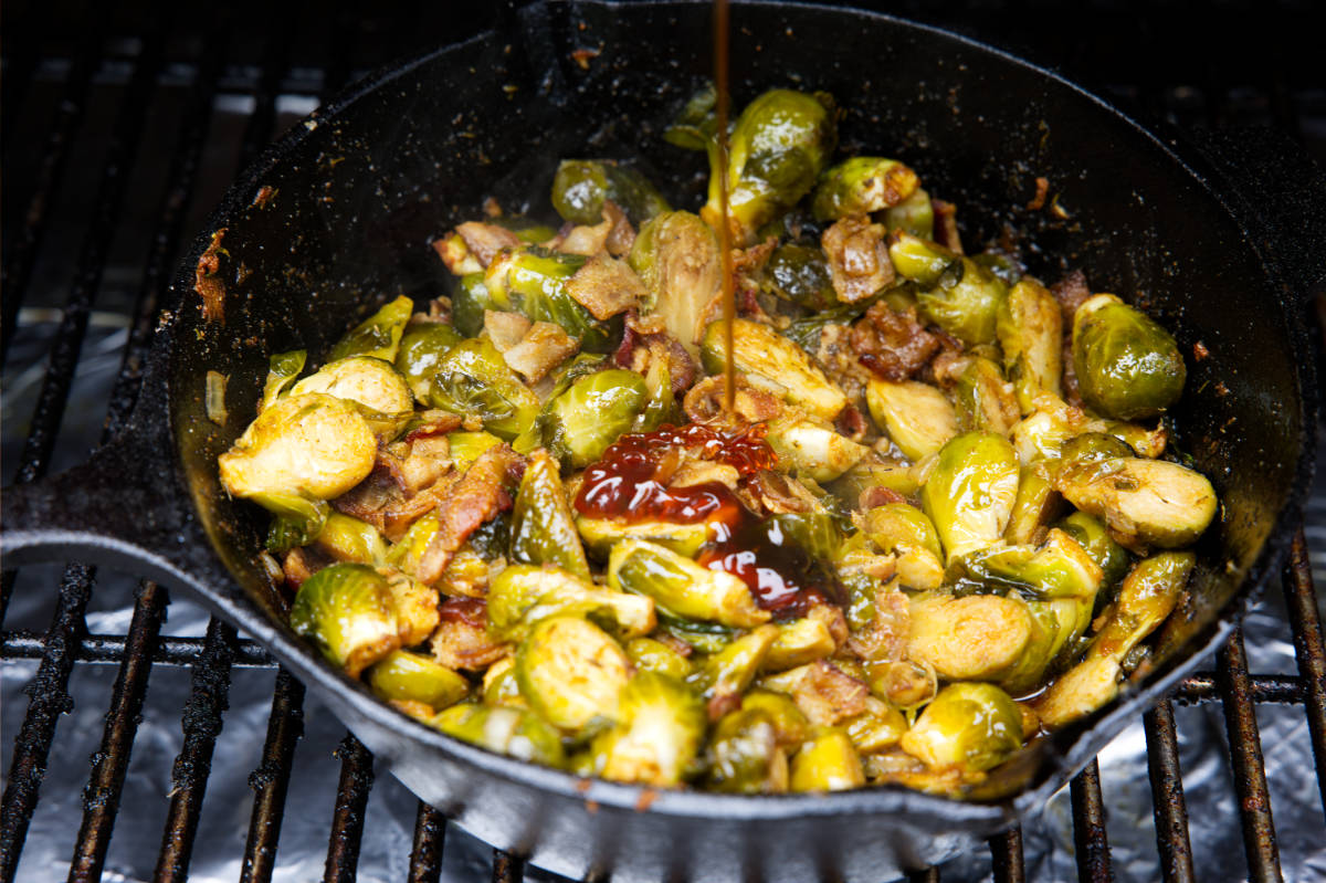 smoked brussels sprouts in a skillet with a drizzle of honey added