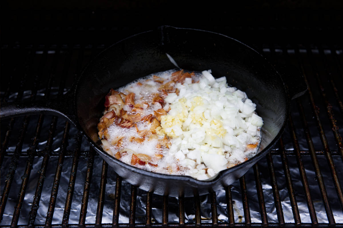 bacon, onions, and garlic cooking in the cast iron skillet