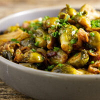 smoked brussels sprouts served in a bowl with a drizzle of hot honey on top