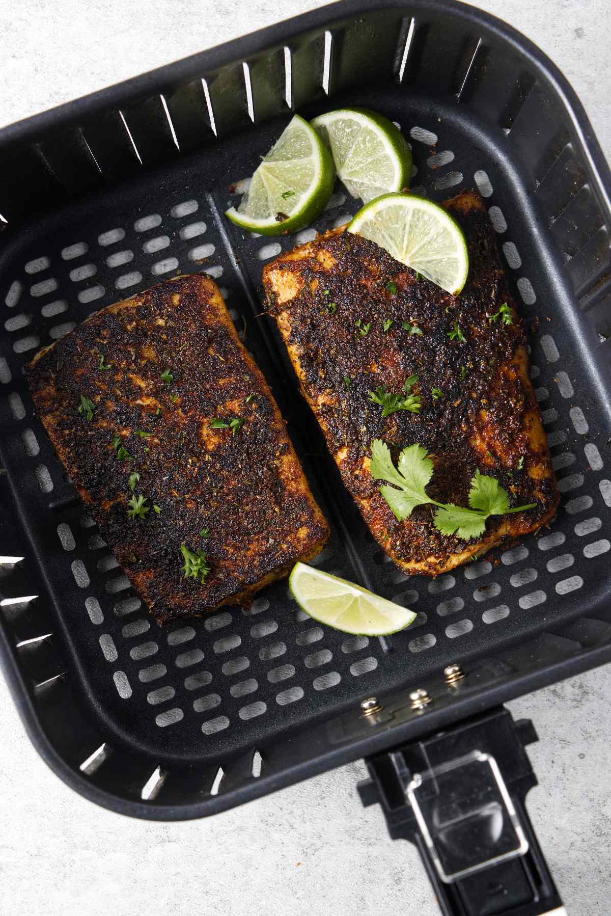 Two mahi mahi fillets in air fryer basket.